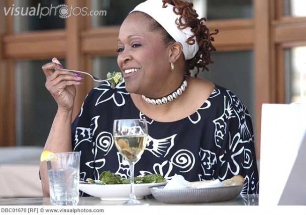 African woman eating salad in cafe